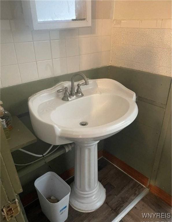 bathroom with wood-type flooring, sink, and tile walls