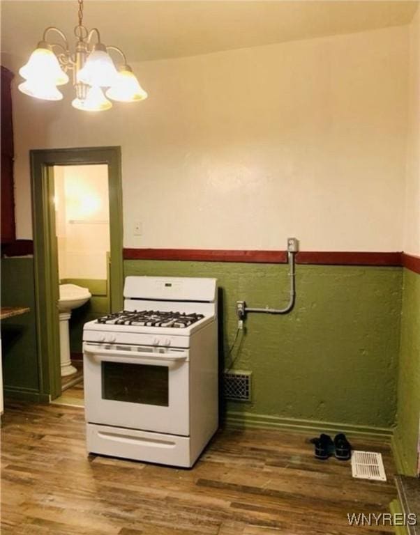 kitchen featuring green cabinetry, wood-type flooring, white gas range oven, and hanging light fixtures