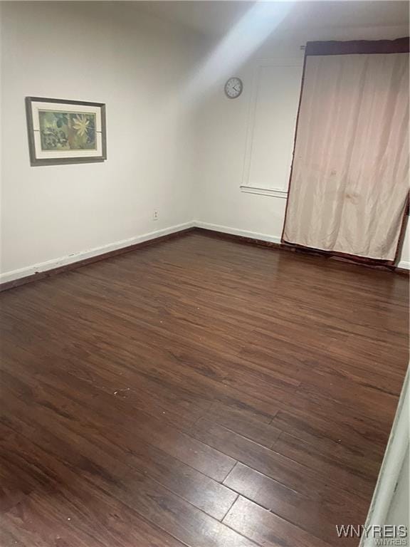 unfurnished room featuring dark hardwood / wood-style flooring and lofted ceiling