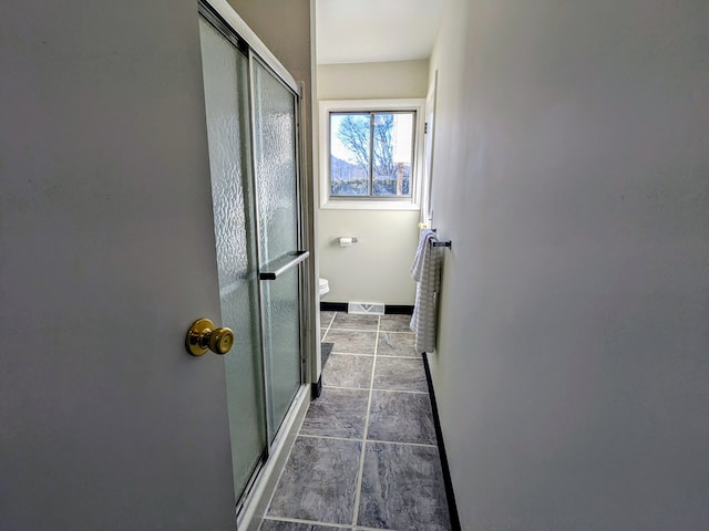 bathroom featuring a shower with shower door and toilet