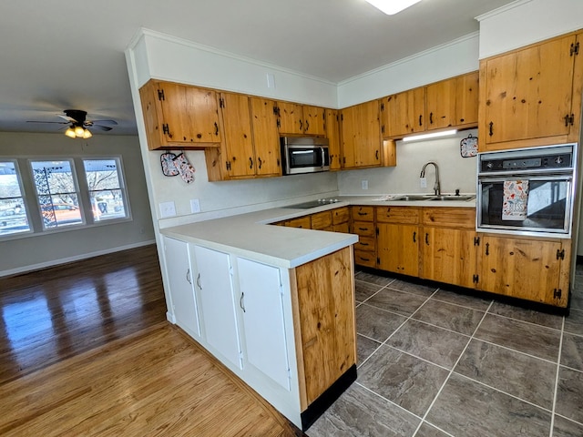 kitchen with sink, ornamental molding, dark hardwood / wood-style flooring, kitchen peninsula, and black appliances