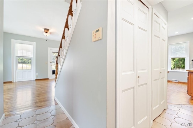 hall with light hardwood / wood-style flooring and a wealth of natural light