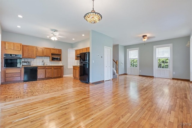 kitchen featuring pendant lighting, sink, ceiling fan, black appliances, and light hardwood / wood-style floors