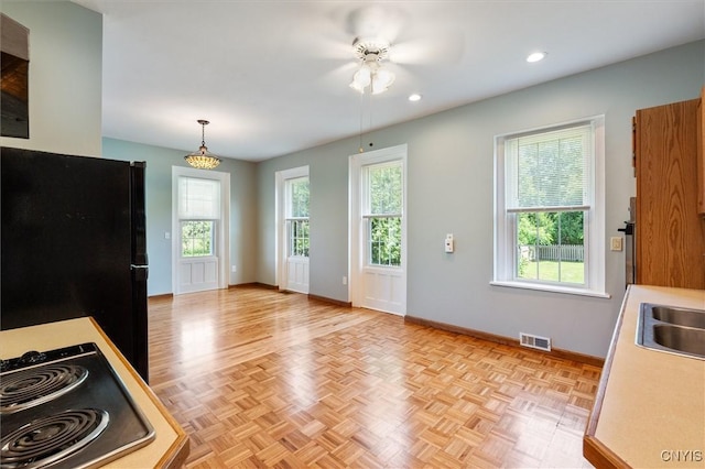 kitchen with pendant lighting, electric stovetop, sink, light parquet flooring, and black fridge