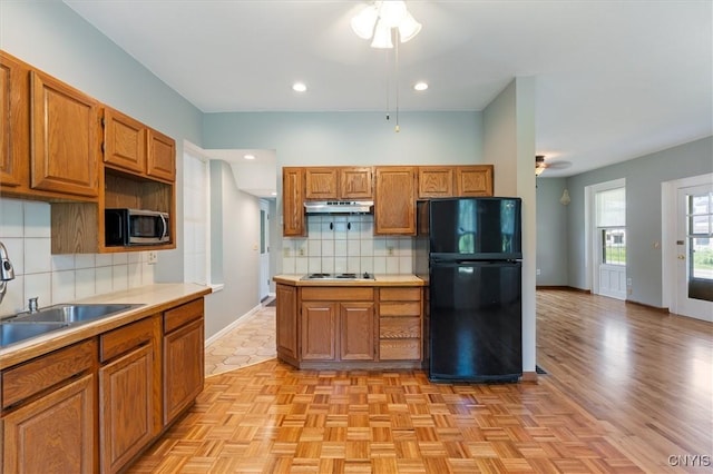 kitchen featuring sink, backsplash, light parquet floors, ceiling fan, and black fridge