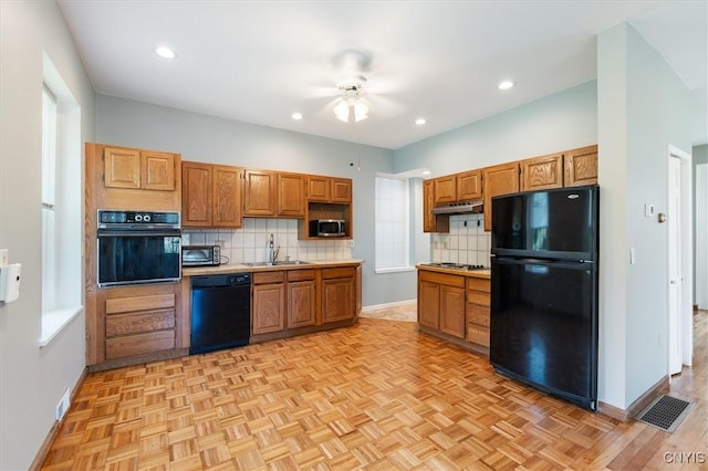 kitchen with sink, ceiling fan, light parquet flooring, decorative backsplash, and black appliances