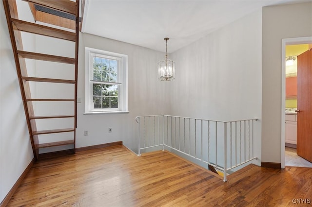 spare room featuring a notable chandelier and light wood-type flooring