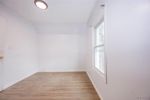 spare room featuring lofted ceiling and light wood-type flooring