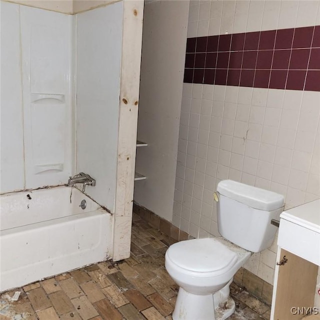 full bathroom with washtub / shower combination, vanity, toilet, and tile walls