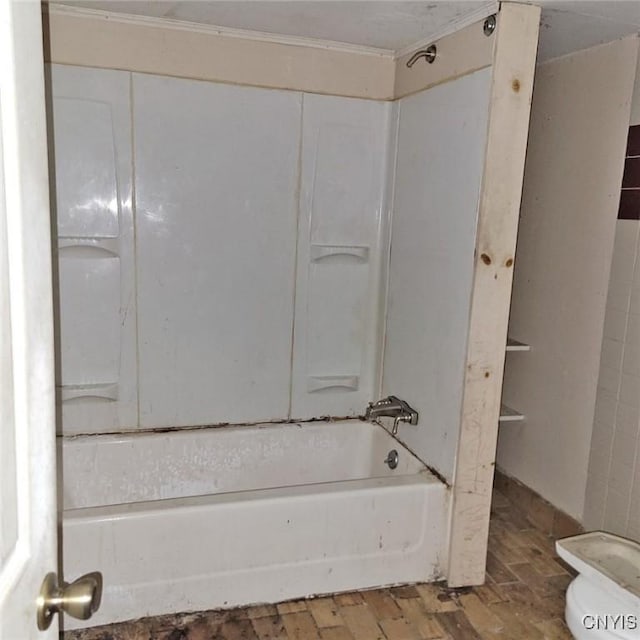 bathroom with hardwood / wood-style floors, shower / washtub combination, and toilet