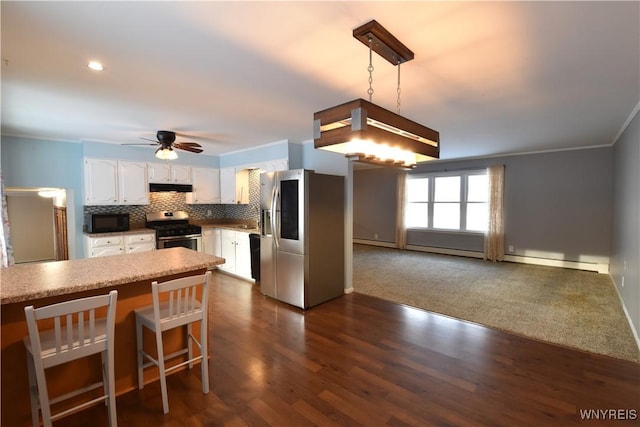 kitchen featuring appliances with stainless steel finishes, white cabinets, decorative backsplash, hanging light fixtures, and ornamental molding