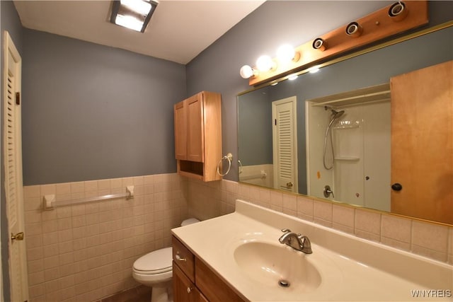 bathroom featuring vanity, a shower, tile walls, and toilet