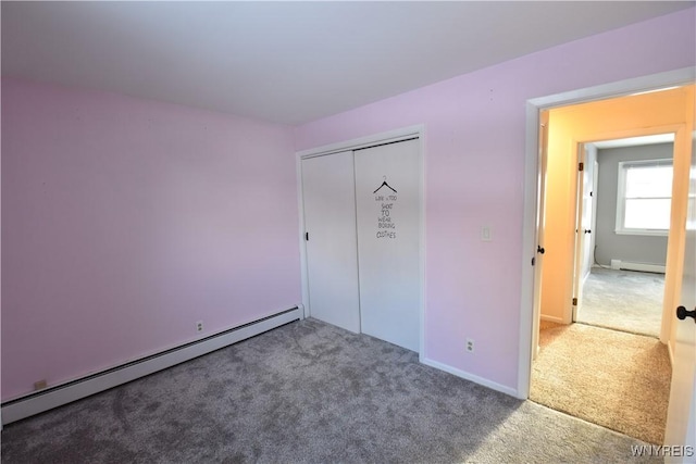 unfurnished bedroom with baseboard heating, carpet flooring, and a closet