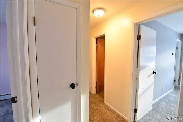 hallway with light colored carpet, ornamental molding, and a baseboard heating unit