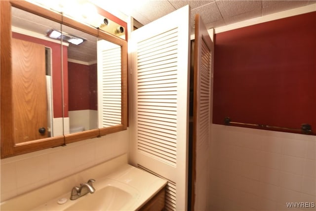 bathroom with vanity, toilet, and tile walls