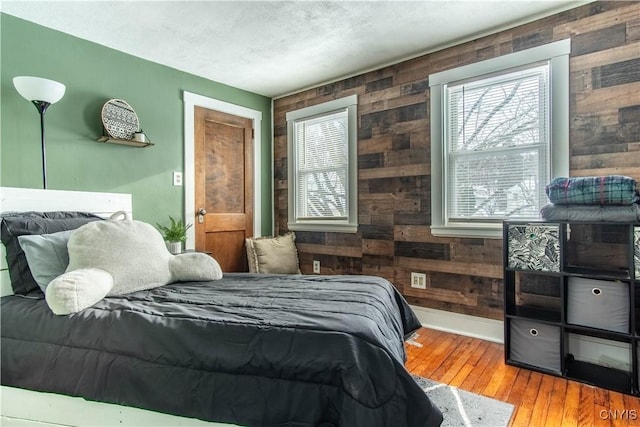 bedroom with hardwood / wood-style floors, a textured ceiling, and wood walls