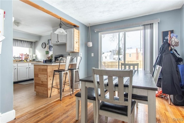 dining area with a textured ceiling and light hardwood / wood-style flooring