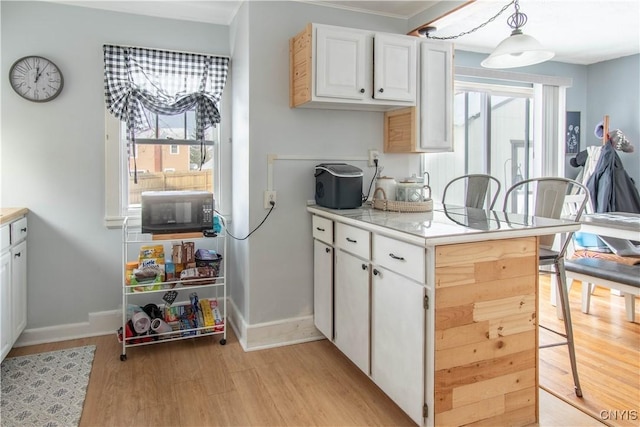 kitchen with pendant lighting, white cabinets, and light hardwood / wood-style floors