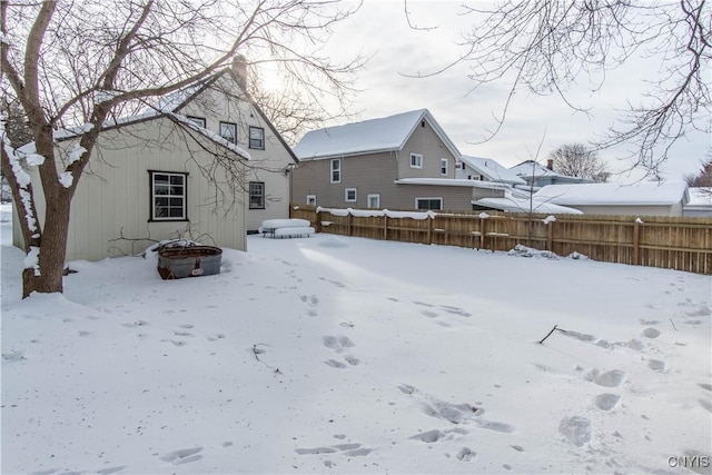 snow covered rear of property featuring an outdoor fire pit