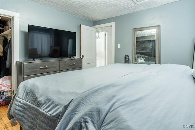 bedroom with a closet, a spacious closet, hardwood / wood-style floors, and a textured ceiling