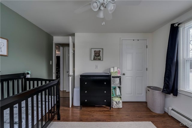 bedroom featuring dark hardwood / wood-style flooring, a baseboard heating unit, and ceiling fan