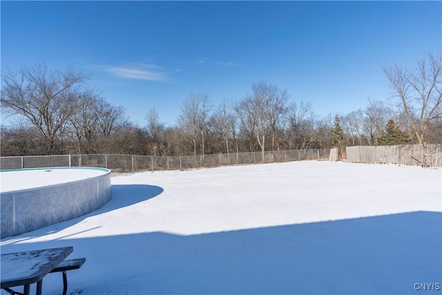 yard layered in snow with a fenced in pool