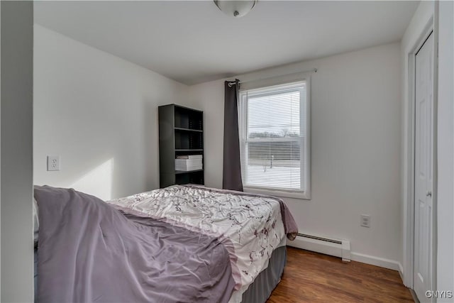 bedroom with baseboard heating, dark wood-type flooring, and a closet