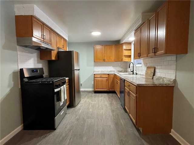 kitchen featuring sink, gas range, tasteful backsplash, stainless steel dishwasher, and light hardwood / wood-style floors