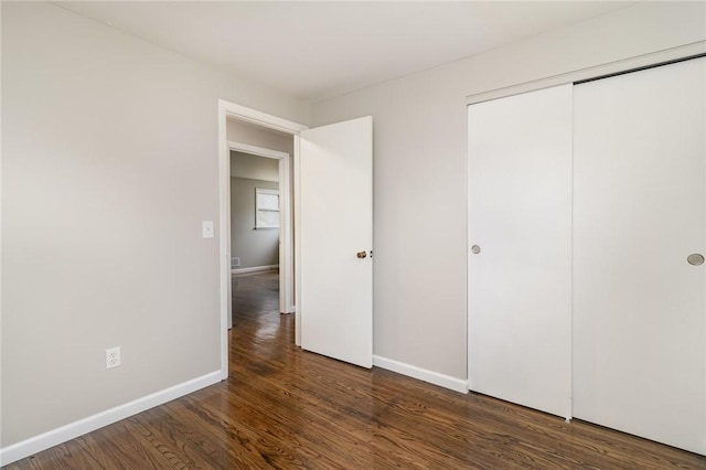 unfurnished bedroom featuring dark hardwood / wood-style flooring and a closet