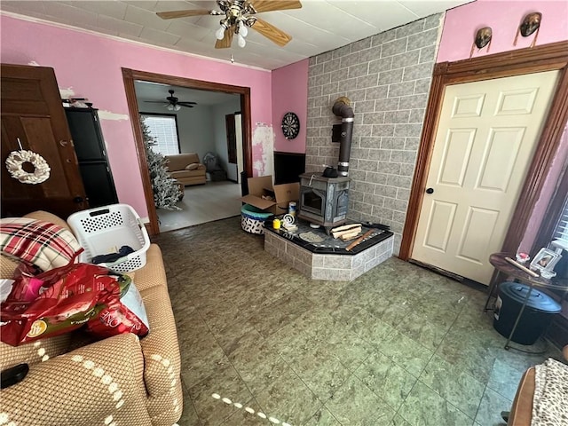 living room with a wood stove and ceiling fan