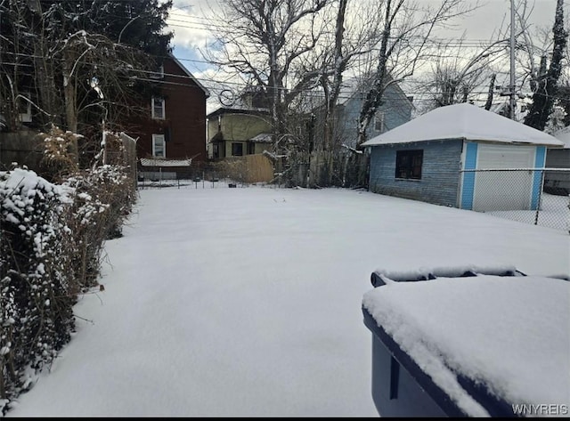 yard covered in snow featuring a garage and an outbuilding