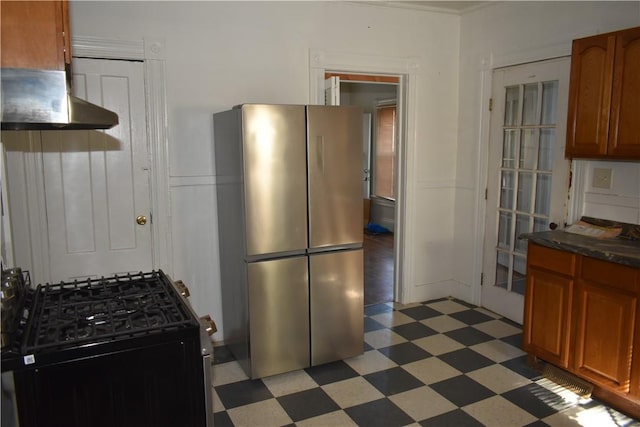 kitchen with ventilation hood, light floors, freestanding refrigerator, range with gas cooktop, and brown cabinets