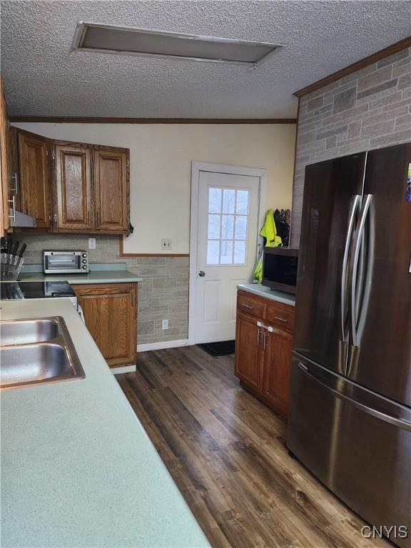 kitchen with sink, crown molding, dark wood-type flooring, stainless steel appliances, and a textured ceiling