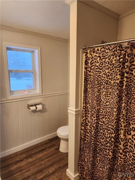 bathroom featuring hardwood / wood-style flooring, ornamental molding, walk in shower, and toilet