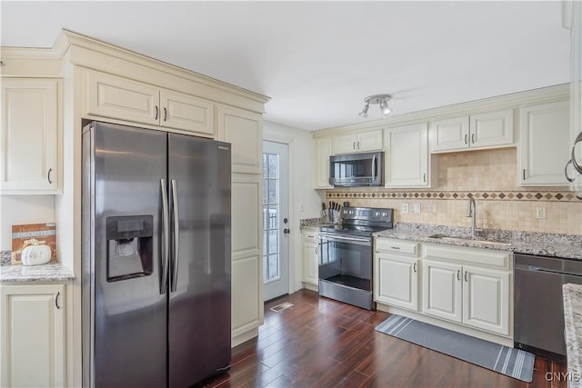 kitchen with sink, dark wood-type flooring, stainless steel appliances, light stone counters, and decorative backsplash