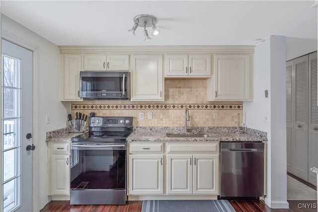 kitchen with tasteful backsplash, appliances with stainless steel finishes, sink, and light stone counters