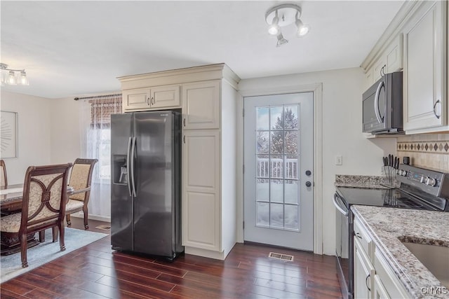 kitchen with light stone counters, dark wood-type flooring, and stainless steel appliances