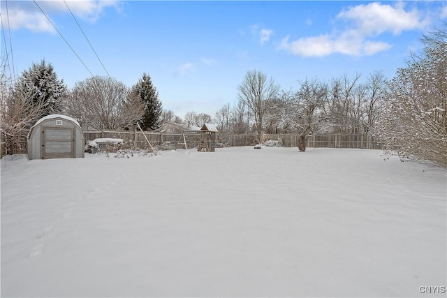 yard layered in snow featuring a garage and an outbuilding