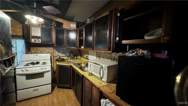 kitchen with light hardwood / wood-style floors, white gas range, ceiling fan, and decorative backsplash