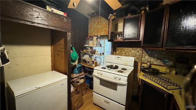 kitchen featuring refrigerator, dark brown cabinets, light hardwood / wood-style flooring, white range oven, and backsplash