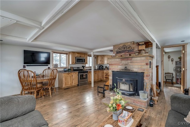 living room featuring light hardwood / wood-style floors, beamed ceiling, and a wood stove