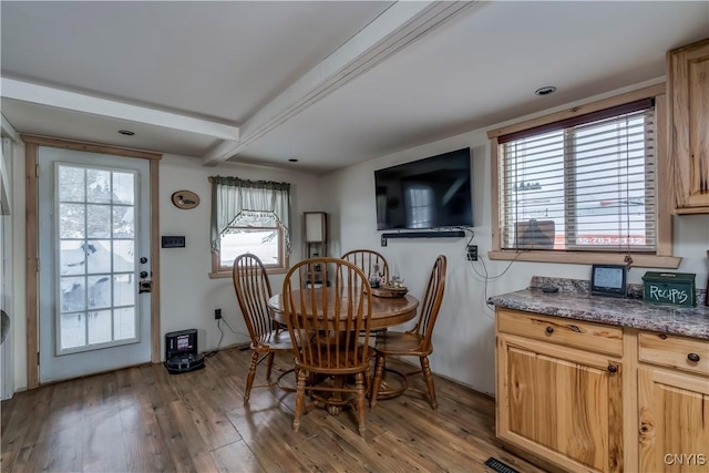 dining space with beam ceiling and hardwood / wood-style floors