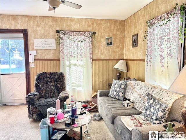 carpeted living room with wooden walls and ceiling fan