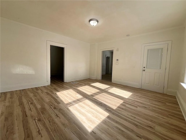 spare room featuring ornamental molding and light hardwood / wood-style floors