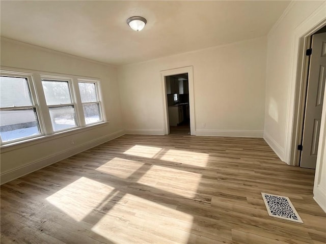 spare room featuring crown molding and light hardwood / wood-style flooring