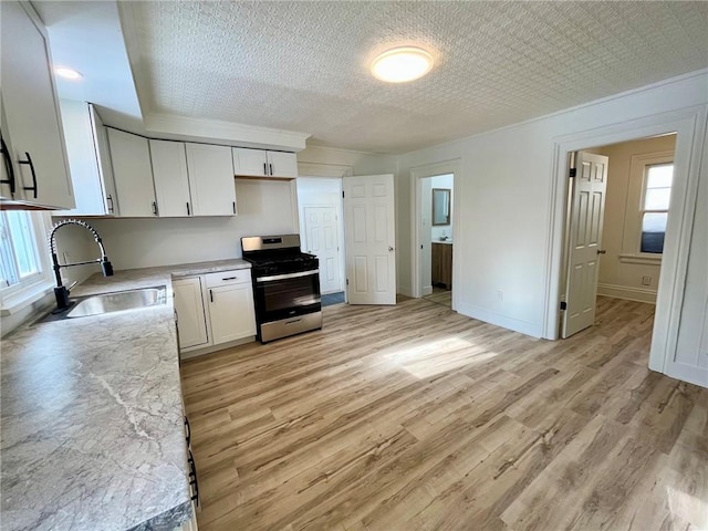 kitchen with white cabinetry, stainless steel range with gas cooktop, sink, and light hardwood / wood-style floors