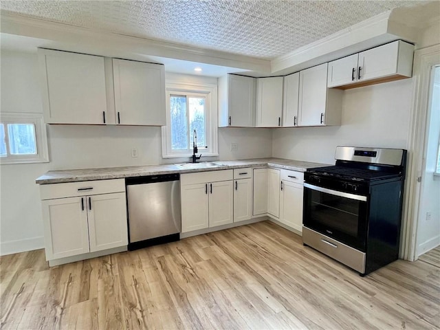 kitchen featuring stainless steel appliances, sink, white cabinets, and light hardwood / wood-style floors