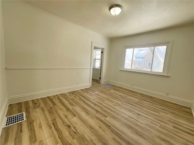 empty room featuring crown molding and light hardwood / wood-style floors