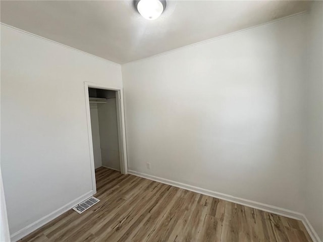 unfurnished bedroom featuring ornamental molding, a closet, and light hardwood / wood-style flooring