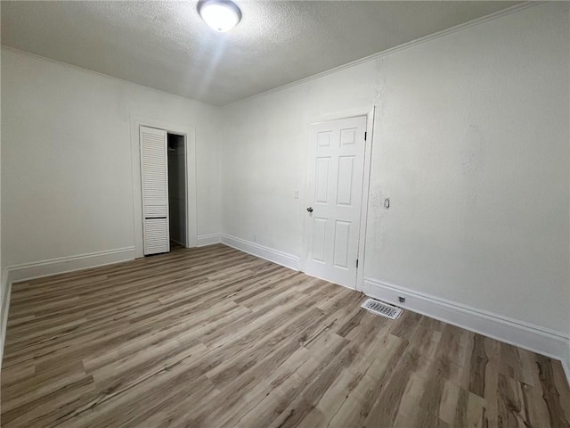 unfurnished room with a textured ceiling and light wood-type flooring